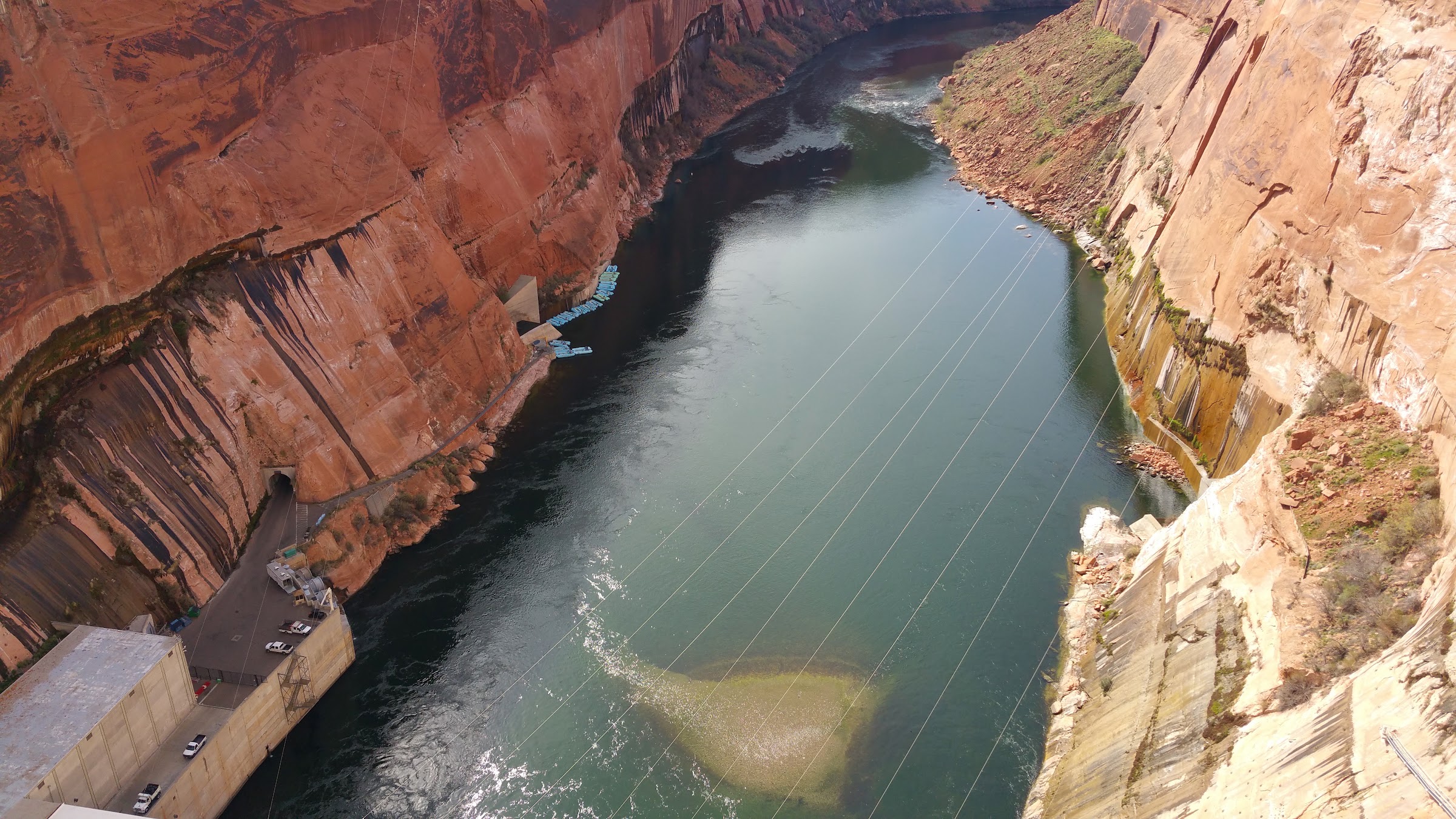 Looking downstream from Glen Canyon Dam: sandstone walls, the river, and the dam, with no people.